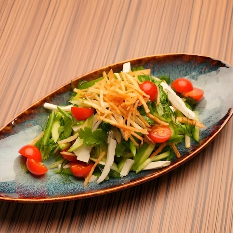 A fresh salad with cherry tomatoes, green vegetables, white cheese, and crispy fried potato sticks.